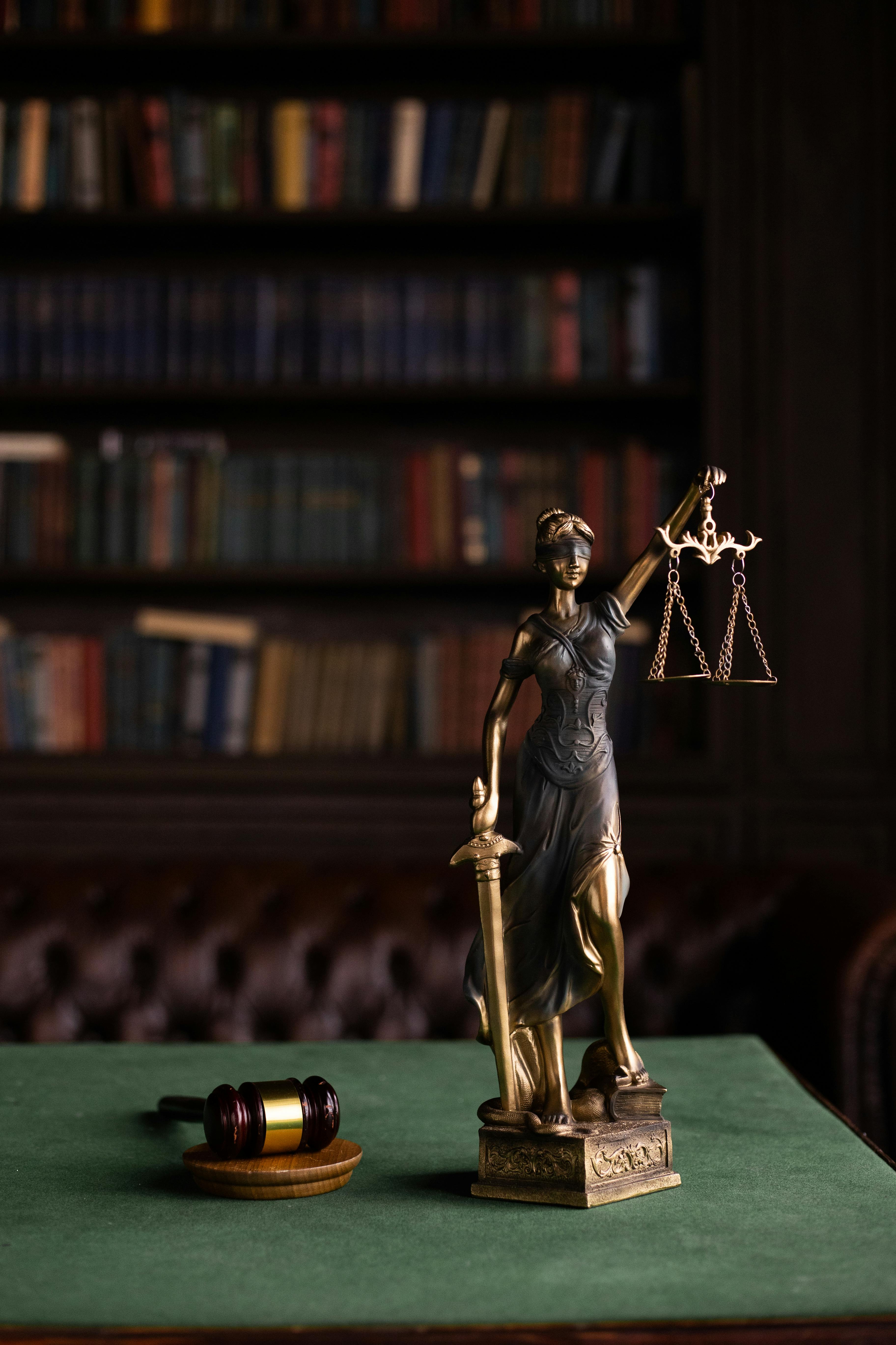 Current image: Lady Justice and gavel on a table in a classic law library setting.